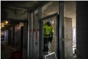 A technician on a step-stool in a new build commercial space