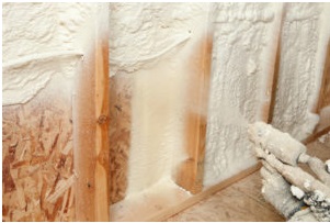 A technician applying spray foam insulation to the wall of a new build