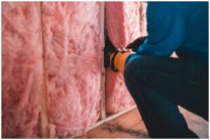 A technician installing fiberglass batt insulation